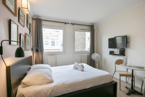 um quarto com uma cama com lençóis brancos e uma janela em Cozy studio 10 min from Eiffel Tower Invalides Beaugrenelle em Paris