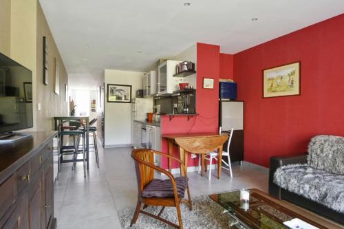 un salon avec un mur d'accent rouge dans l'établissement Maison Escola avec jardin - Welkeys, à Marcq-en-Barœul