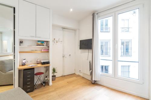 an apartment with a desk in a room with windows at Cosy studio in Paris close to Grands Boulevards and Bourse - Welkeys in Paris