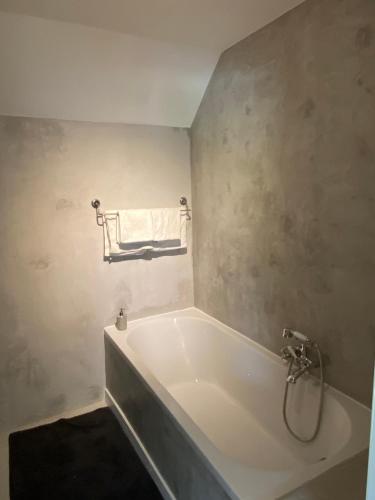 uma banheira branca na casa de banho com uma toalha em Horenbecca studio met tuin zwembad & bistro em Horebeke