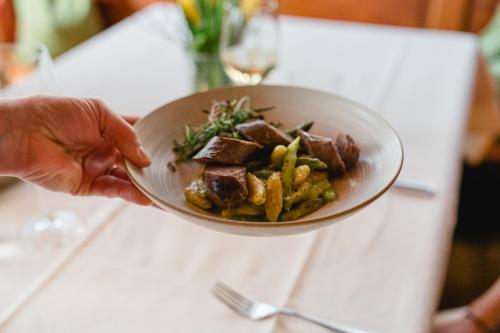 a person holding a bowl of food on a table at Landhotel Hirschen in Oberwolfach