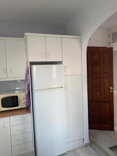 Un refrigerador blanco en una cocina con microondas. en Estudio Duquesa Golf Sierra y Mar, en Manilva