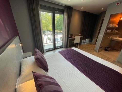 - une chambre avec un grand lit et un balcon dans l'établissement Hôtel Logis Restaurant La Fontaine, à Mantry