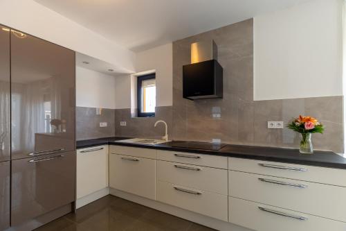 a kitchen with white cabinets and a tv on the wall at Villa Family and Friends private heated pool with jacuzzi in Zadar