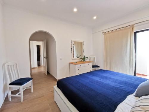 ein weißes Schlafzimmer mit einem blauen Bett und einem Stuhl in der Unterkunft Lagos Sea View Apartment in Lagos