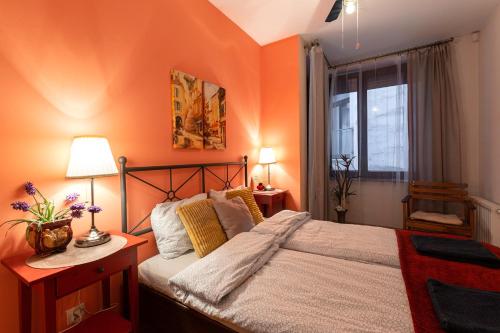 sypialnia z pomarańczowymi ścianami, łóżkiem i oknem w obiekcie Negroni Apartments w Krakowie