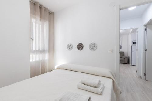 a white bedroom with a bed with towels on it at ARABIAL DELUXE III in Granada