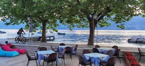 a person riding a bike past tables and chairs by the water at Hotel S.Maria in Brenzone sul Garda