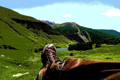 a person with their feet up on a grassy mountain at La Foux d'Allos Vacances nature Espace Lumière in La Foux