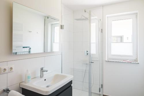 a white bathroom with a sink and a shower at Dünenquartier Apartment 27 in Zingst