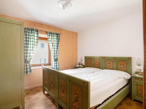 a bedroom with a green bed and a window at Ciasa Lino Sas da le Doudesc in Pozza di Fassa