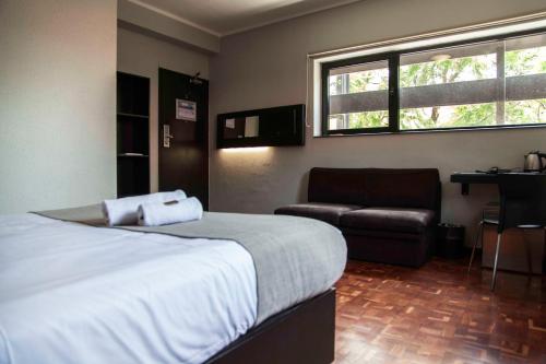 1 dormitorio con cama, sofá y ventana en Inani Hotel Morning Star en Pretoria