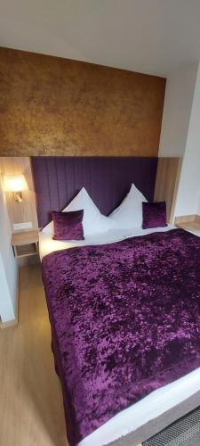 a bedroom with a large bed with purple sheets and pillows at Appartements am Schillergarten in Dresden