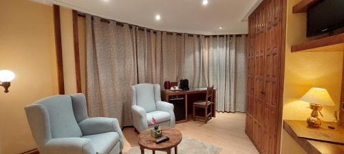 a room with two chairs and a desk with a television at Hosteria Picos De Europa in Potes
