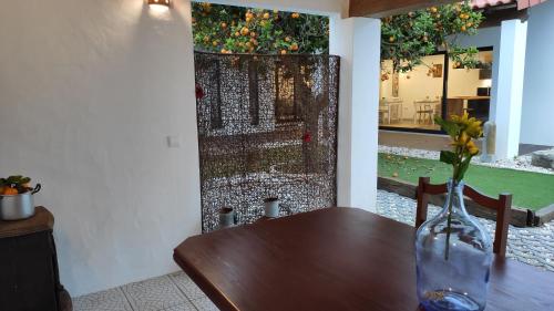 a wooden table with a vase of flowers on it at LARANJEIRA das LOIRAS in Óbidos
