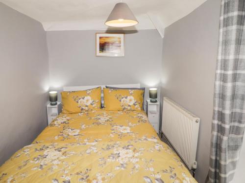 une chambre avec un lit jaune avec des fleurs dessus dans l'établissement Kooky Cottage, à Brecon