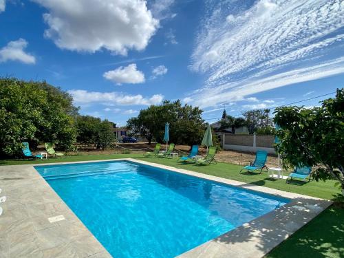 a swimming pool with chairs and a blue sky at The Farm Tiny House - Tiny Casa in Chiclana de la Frontera