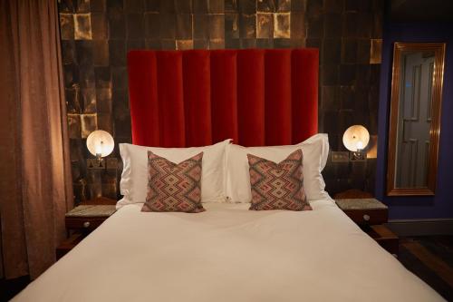 1 cama grande con 2 almohadas y cortina roja en The Kings Arms Pub & Boutique Rooms, en Londres