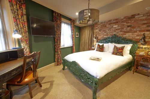 a bedroom with a bed with a bench and a piano at The Kings Arms Pub & Boutique Rooms in London