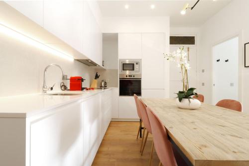 a kitchen with white cabinets and a wooden table with chairs at Reina Sofia Boutique II by Madflats Collection in Madrid