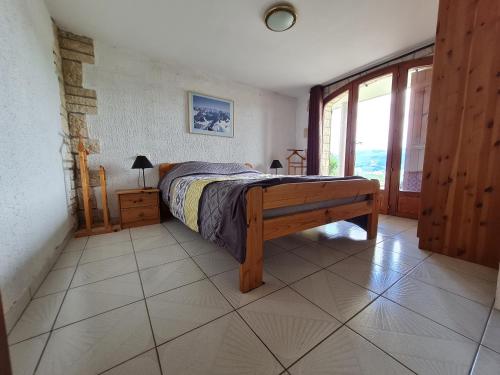 a bedroom with a bed and a large window at Ô Panoragite - Gîte familial in Boëge