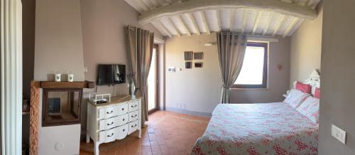 a bedroom with a bed and a tv and a dresser at Poggio ai Gelsi in Pienza