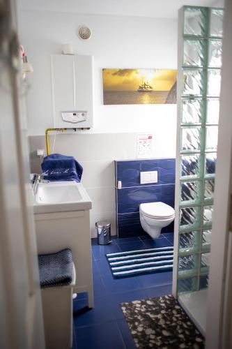 a blue and white bathroom with a toilet and a sink at Apartament Korab in Żarnowska
