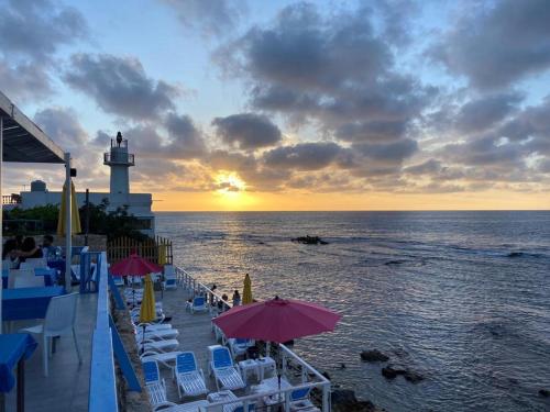 a lighthouse on a beach with chairs and a lighthouse at Asamina Boutique Hotel in Soûr