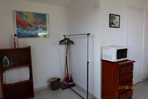 Zimmer mit einem TV und einer Mikrowelle auf der Kommode in der Unterkunft Bungalow climatisé neuf Saint Pierre Ile de la Réunion in Ravine des Cabris