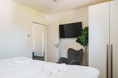 ein Schlafzimmer mit einem Bett und einem Fernseher an der Wand in der Unterkunft Dünenquartier Apartment 17 in Zingst