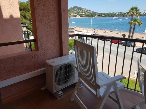 uma varanda com uma cadeira e um ar condicionado e a praia em Les marines Agay em Agay - Saint-Raphaël