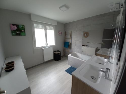 a white bathroom with a sink and a tub at Villa kerneing in Fouesnant