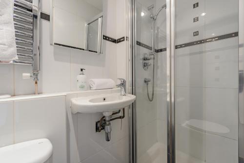 a white bathroom with a sink and a shower at The Rose Street Apartment in Edinburgh