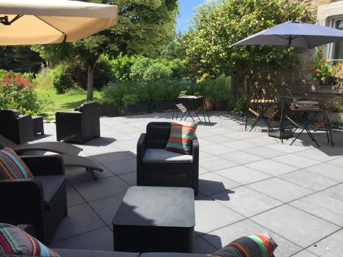 une terrasse avec des chaises, des tables et un parasol dans l'établissement Les 3 Koïs, à Riec-sur-Bélon