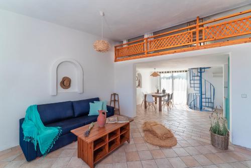 salon z niebieską kanapą i poddaszem w obiekcie Eco Beachfront Villa w mieście Jenadi