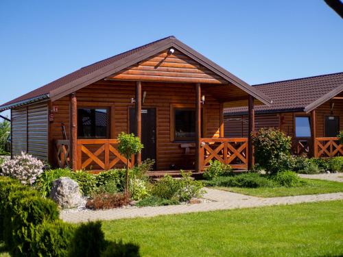 a log cabin with a porch and a yard at Ostoja Maltańska in Jezierzany