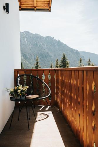 a chair and a table on a balcony with mountains at Cabana Fantanele in Ceahlău