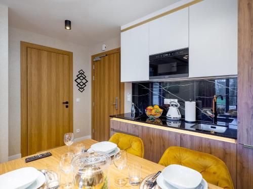 a kitchen with a wooden table with yellow chairs and a counter at Aparthotel Góralski Spa 2 in Białka Tatrzanska