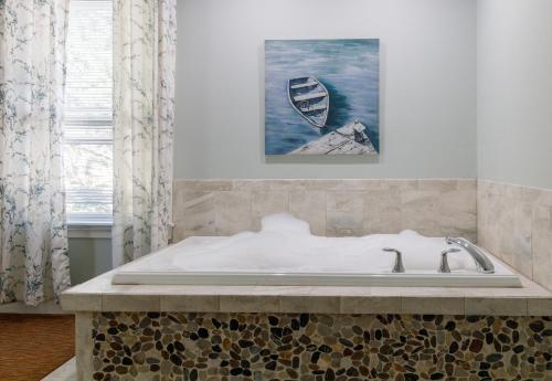 a bath tub in a bathroom with a painting on the wall at Admiral's Inn Resort in Ogunquit