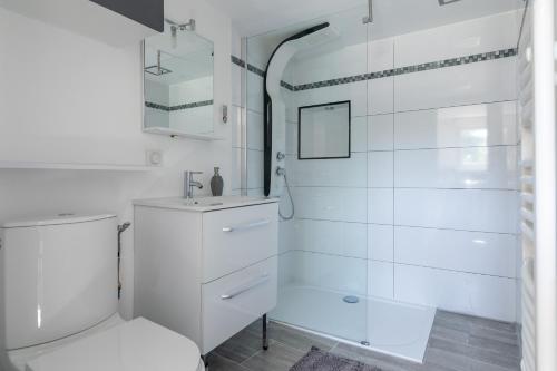 uma casa de banho branca com um WC e um chuveiro em Cosy Corner em Saint-Xandre