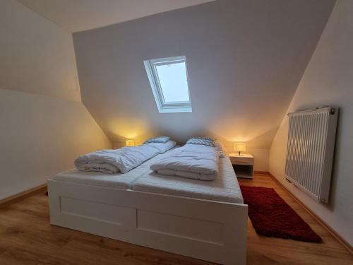 a white bedroom with a bed with a window at Ferienwohnung Schlickwanderer Klein in Neßmersiel