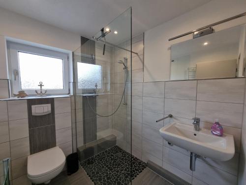 a bathroom with a shower and a sink and a toilet at Ferienwohnung Nordwind in Neßmersiel