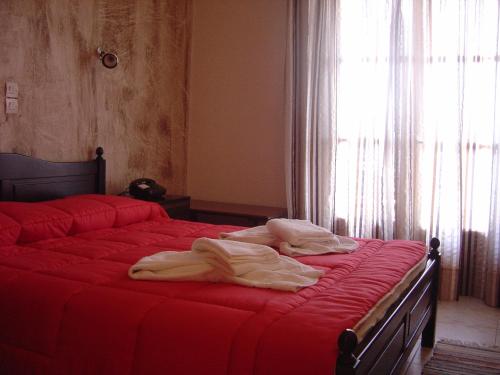 sypialnia z 2 łóżkami z czerwoną pościelą i oknem w obiekcie Porto Lourba w mieście Galaxidi