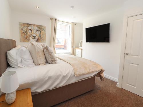 a bedroom with a bed with a television on the wall at Flat 2 in Prestatyn