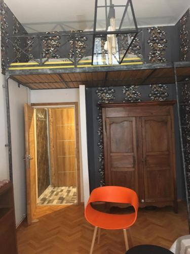 Zimmer mit einem orangenen Stuhl und einer Tür in der Unterkunft Apartament Kopernika z antresolą in Toruń
