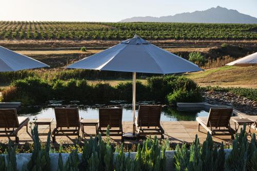 a group of chairs and an umbrella on a patio at Rijk's Guesthouse in Tulbagh