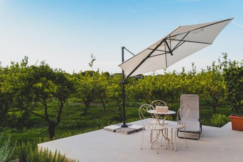 eine Terrasse mit einem Tisch, Stühlen und einem Sonnenschirm in der Unterkunft Il Limoneto Rooms in Terme Vigliatore