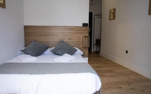 a bedroom with a white bed with a wooden headboard at Balhondo Open Village in Puebla de Alcocer