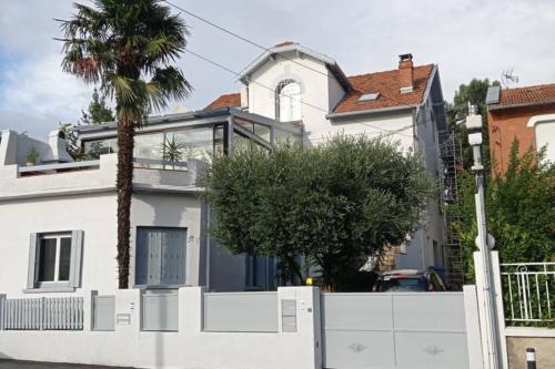a white house with a white fence and a palm tree at Appart indépendant, 1 lit deux personnes et 1 appoint Piscine Jardin Direct Gare Aéroport et jardin in Toulouse