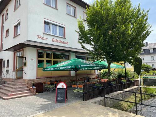 un restaurante con una sombrilla verde frente a un edificio en Landgasthof Zum Heidekrug, en Bad Orb